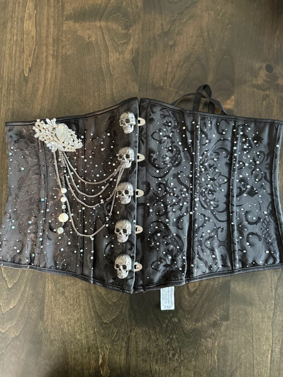 Black corset with skull and crystal embellishments on a wooden surface